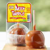 Caramel apple with packaging labeled 'Affy Tapple' on a wooden surface.