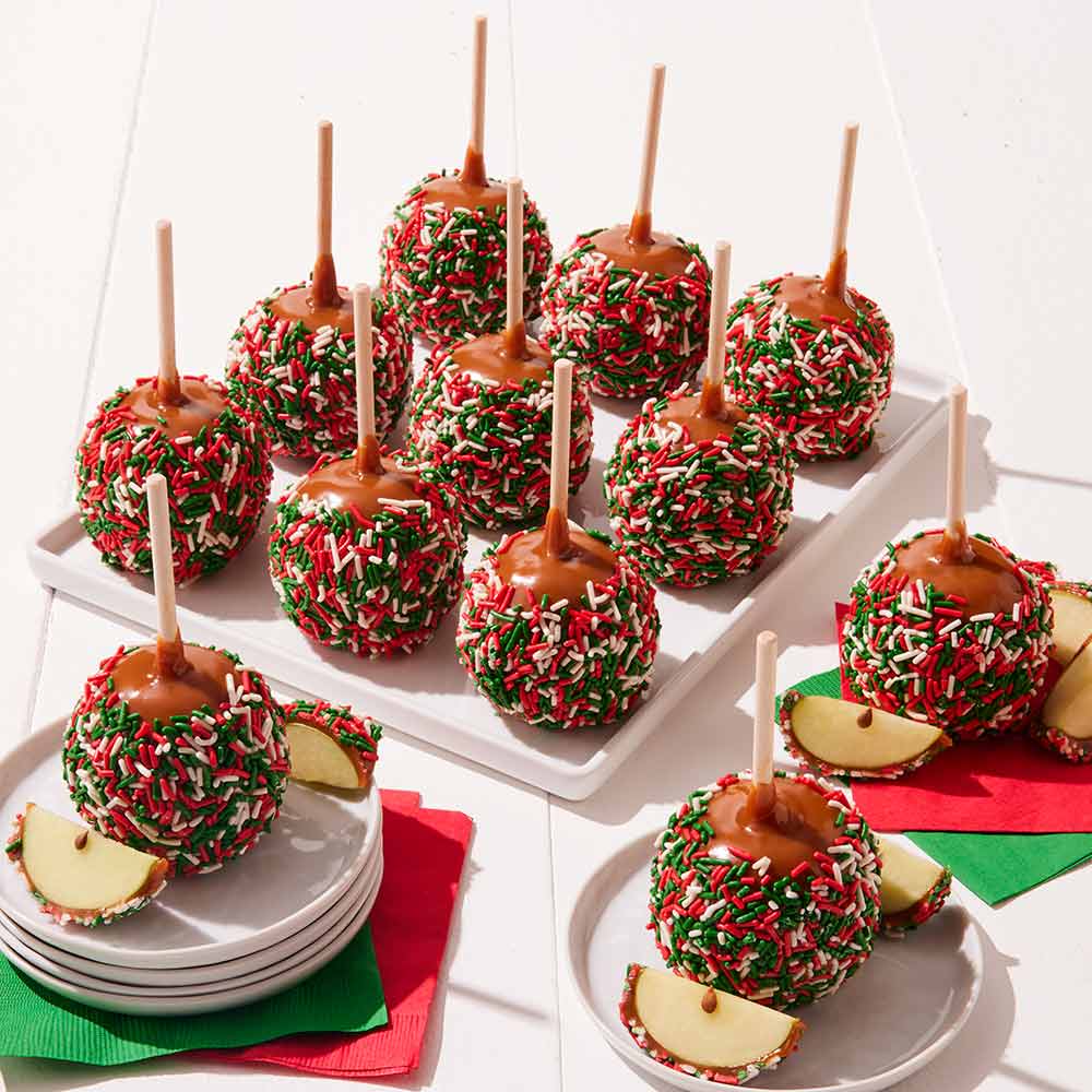 Caramel apples with Christmas sprinkles on a white surface