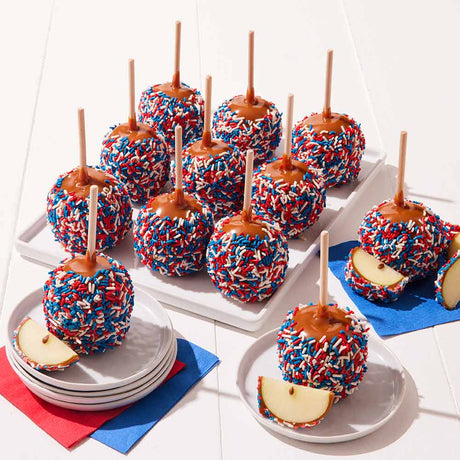 Caramel apples with red, white, and blue sprinkles on a white surface.