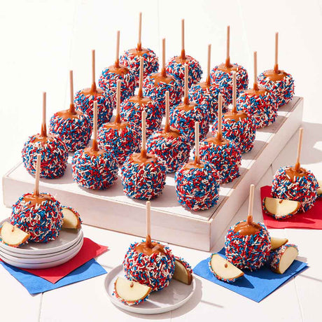 Caramel apples with red, white, and blue sprinkles on a white surface.
