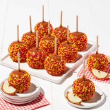 Caramel apples with colorful sprinkles on sticks, served on a white tray and plates.