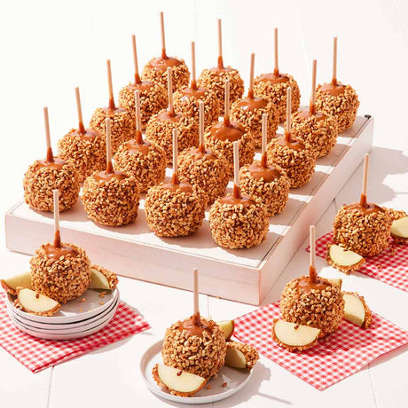 Caramel apples with nuts on sticks displayed on a white stand with red checkered napkins.